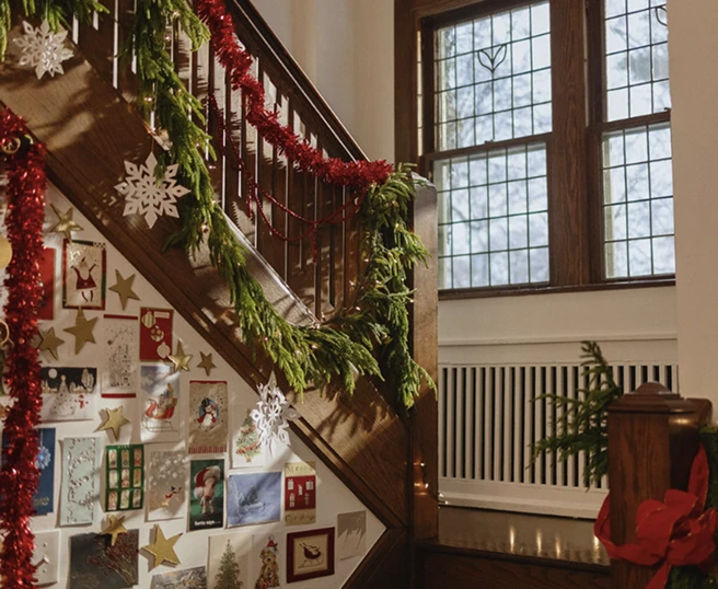 An interior view of a home with a window and staircase displaying holiday garland and greeting cards.
