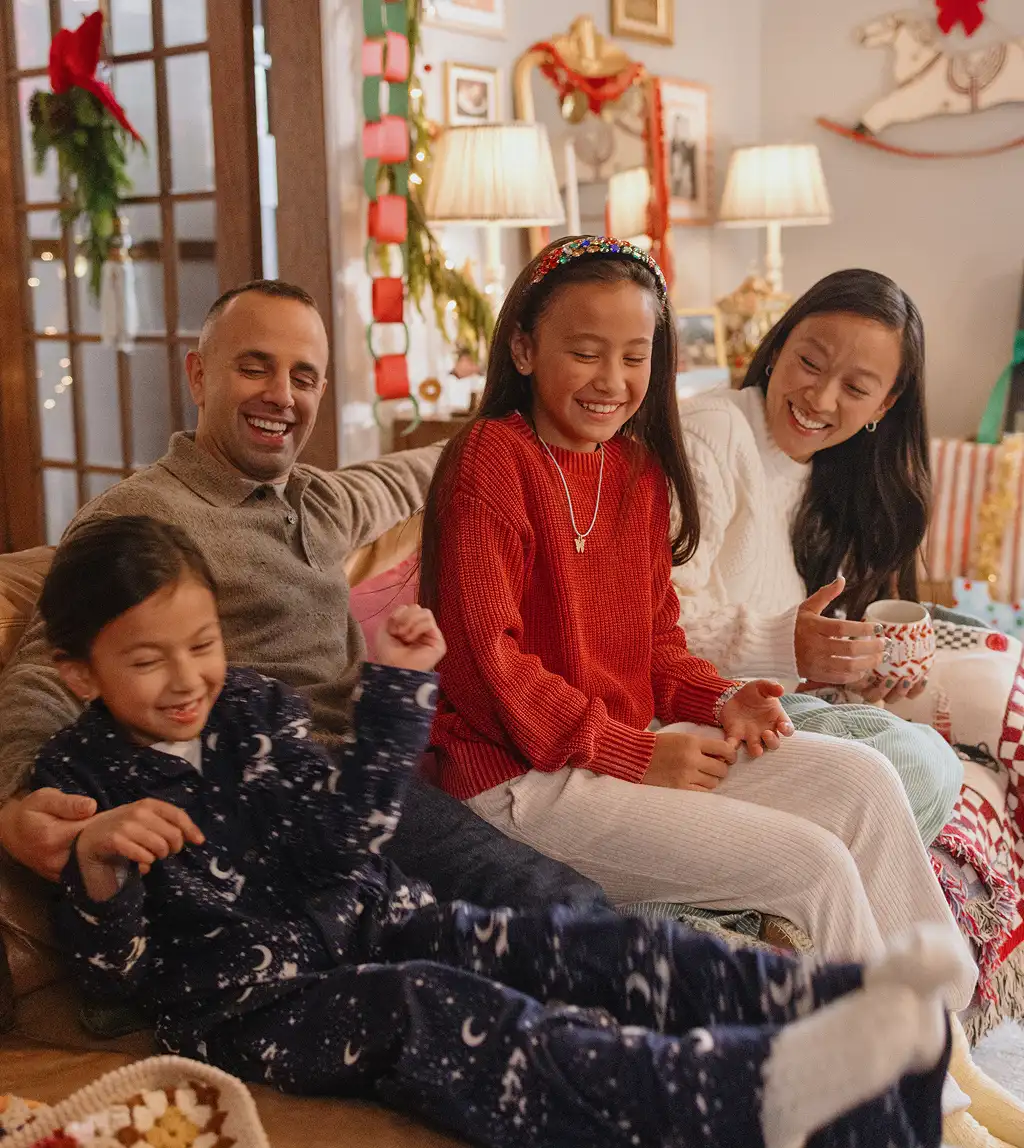 Parents and children laughing together on a couch during the holidays.
