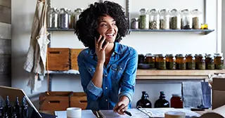 A black woman smiling and talking on the phone.