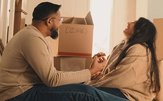 Two new homeowners enjoy a laugh over take-out pizza while taking a break from unpacking.