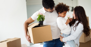 Two young parents hold their toddler as they work on packing for a move.