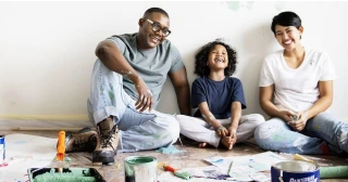 A multiracial family sits on the floor while taking a break from painting a room.