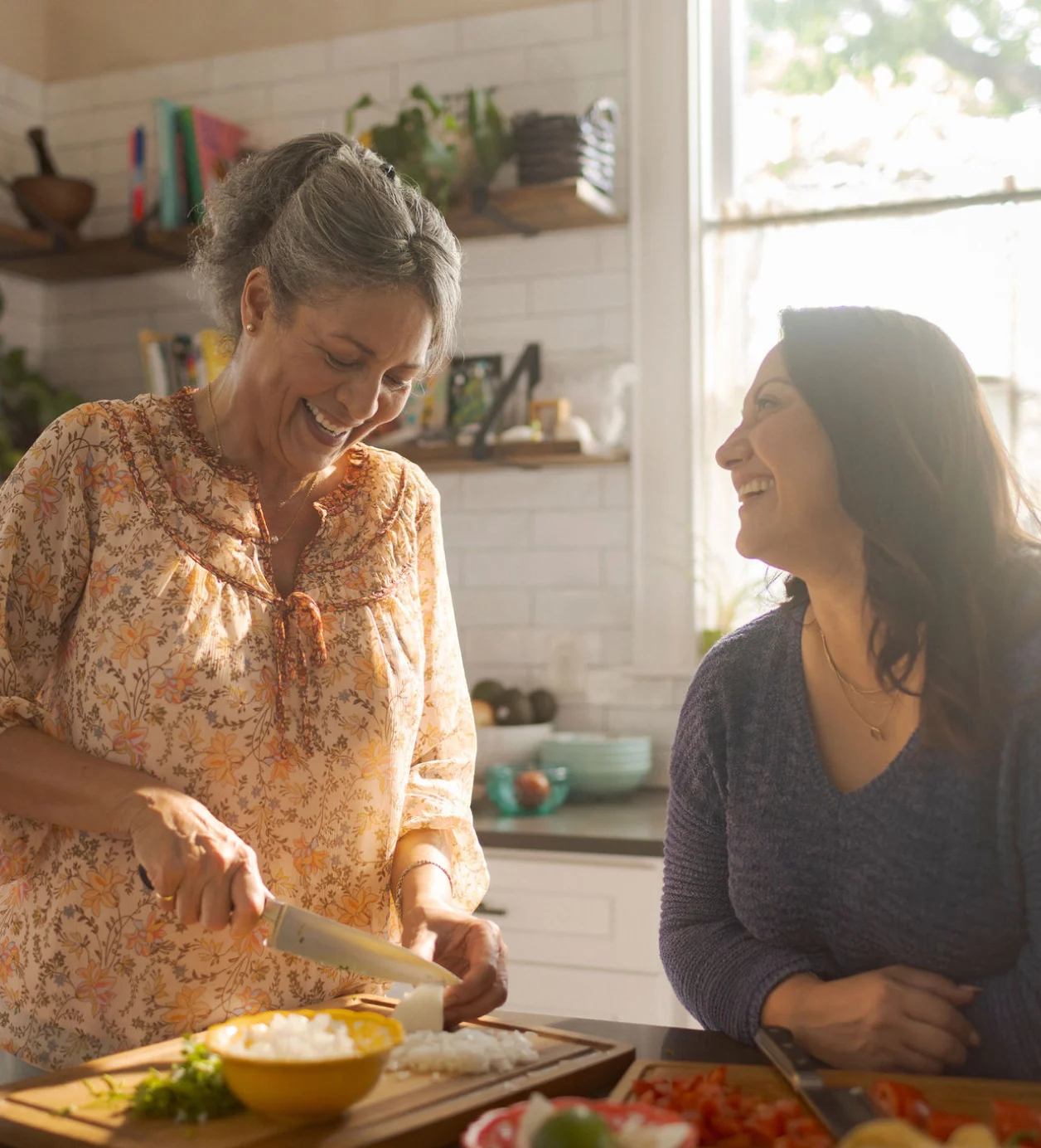 Madre anciana e hija de mediana edad cocinando juntas en la cocina.