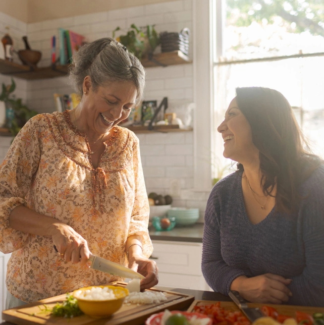 Madre anciana e hija de mediana edad cocinando juntas en la cocina.