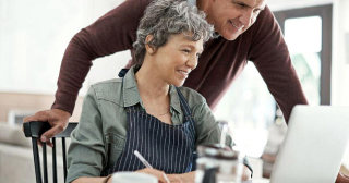 A middle-aged white couple research refinancing on their laptop.