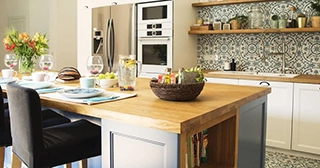 Interior of a kitchen with a large island and mosaic tile backsplash.