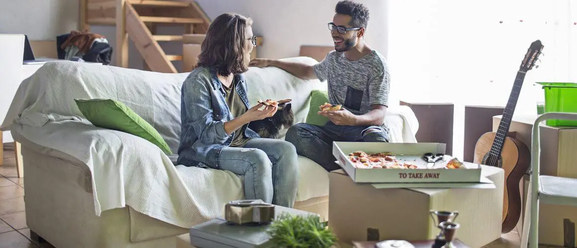 A middle-aged couple pause to eat some pizza while unpacking as they move into their new home.