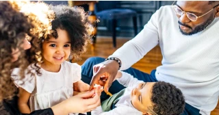 Multicultural family with two children hanging out on the floor