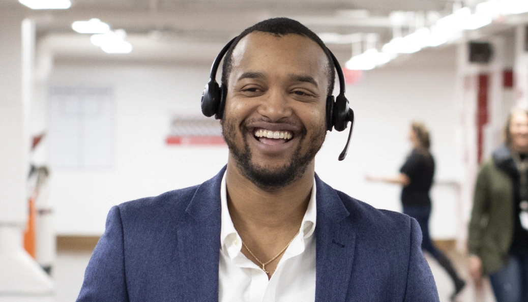 Rocket Mortgage team members are here to help new clients, like this smiling Black man wearing a headset, white shirt and navy blazer.