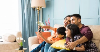 An Indian family of four enjoys some time together on a couch in their living room. 