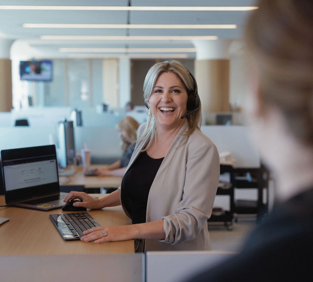 A Home Loan Expert at Rocket Mortgage, like this woman wearing a beige jacket standing at a computer desk, can help with Verified Approval Letters.