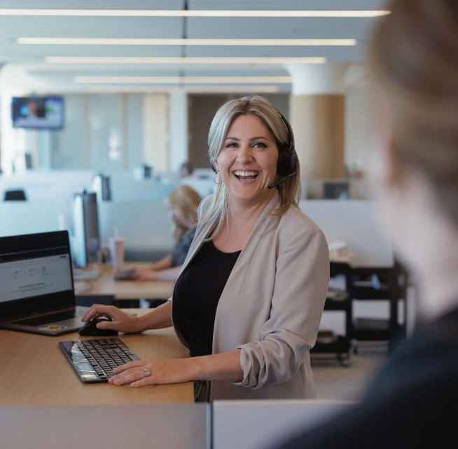 A Home Loan Expert at Rocket Mortgage, like this woman wearing a beige jacket standing at a computer desk, can help with Verified Approval Letters.