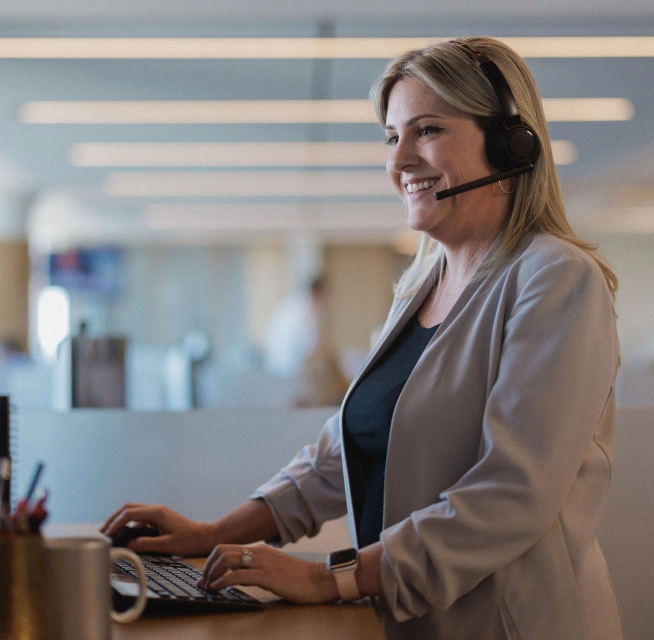 Loan officers at Rocket Mortgage  like this woman wearing a beige blazer and a headset at computer keyboard are focused on the success of our real estate agent partners.