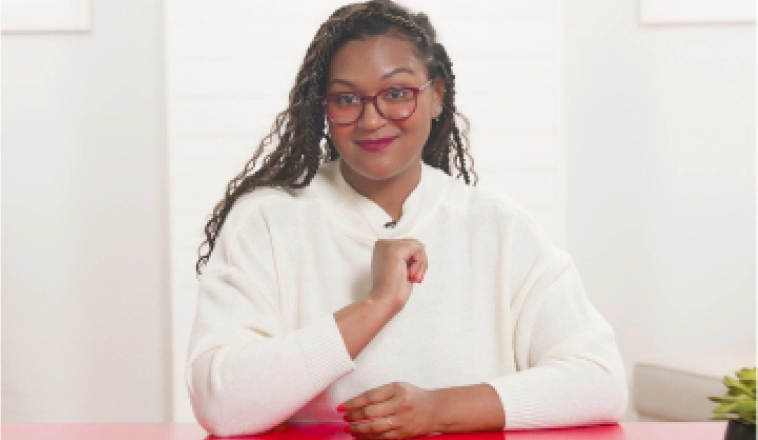 The Red Desk spokeswoman sitting at a red desk wearing a white shirt.