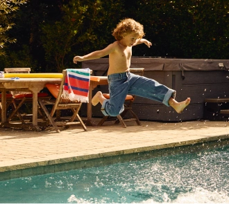 Un niño pequeño salta a una piscina del patio trasero.