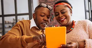 A man and woman discussing something on a tablet.