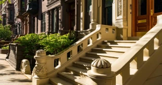 A close-up of a porch on a row of brownstones on a city street.