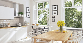 White modern kitchen with a dining table and the windows open.