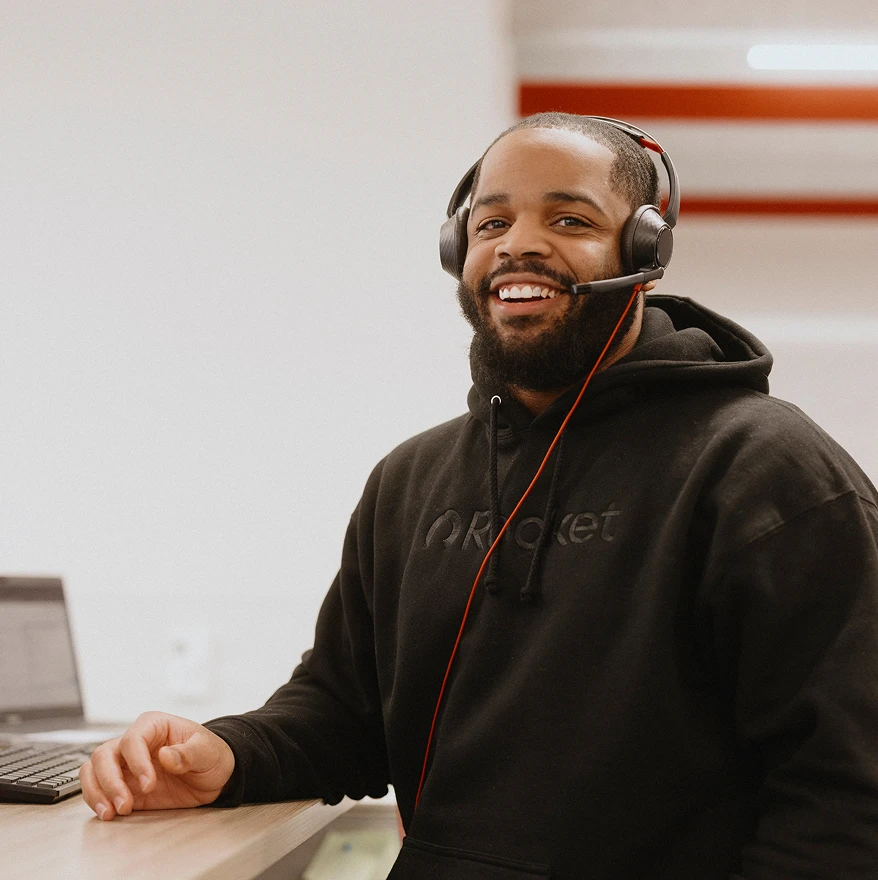 Alt text: A Rocket Mortgage team member smiles while wearing a headset and black hoodie.