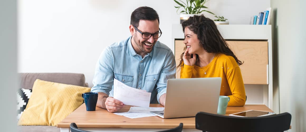 Couple reviewing finances at dining table.