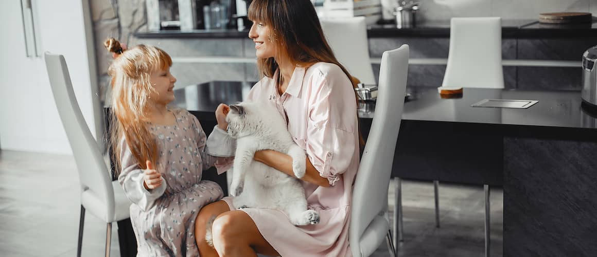 RHB Assets From IGX: Smiling mother and daughter sitting on a couch with a tabby cat.