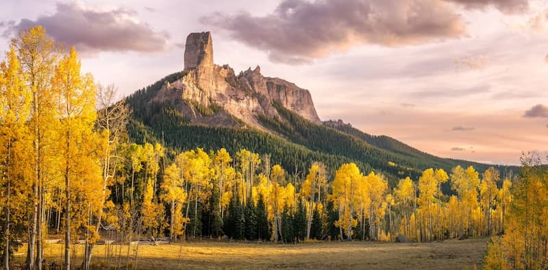 Courthouse mountain in Colorado with cloudy skies and birch trees.