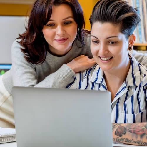 A couple looking at a laptop together, potentially engaging in activities such as browsing or working online as a team.