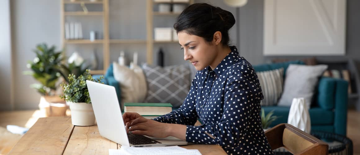 A young woman working on a laptop, possibly in a home or office setting.