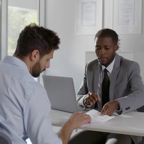 Two men reviewing paperwork in a modern office.