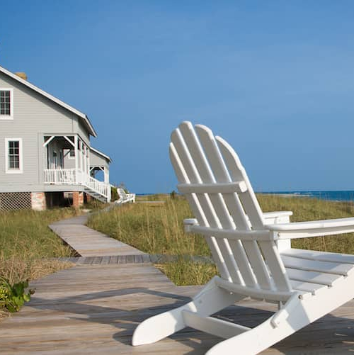 Two beach chairs on a boardwalk, depicting a serene beachside setting.