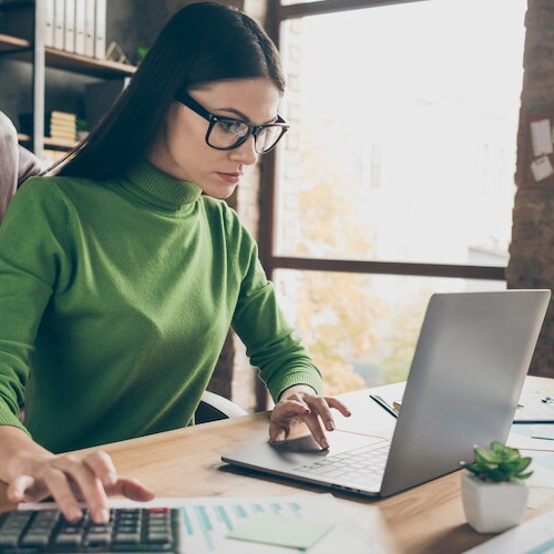 RHB Assets From IGX: Woman sitting at a table, calculating home value with documents and a calculator.