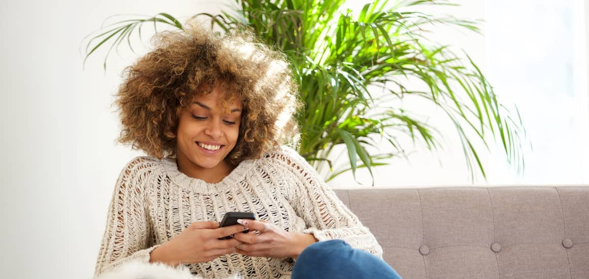 A woman sitting on a couch talking on the phone about financing.