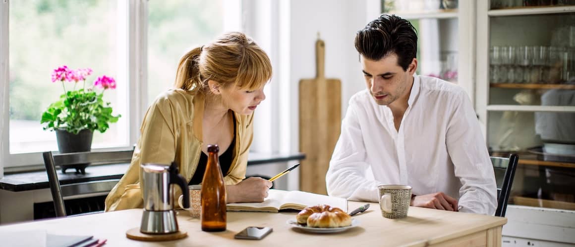 Man and woman going over details of partnership at kitchen table.