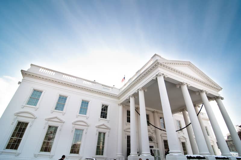 View of The White House from below at an angle with blue sky background.