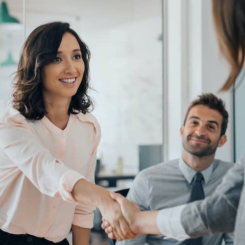 Two women shaking hands, potentially symbolizing a successful agreement or partnership.