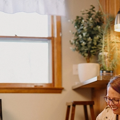 Woman petting two dogs on floor in kitchen.