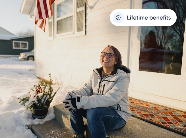 Smiling woman in winter jacket sitting on snowy front steps under an American flag, with text reading "Lifetime benefits."