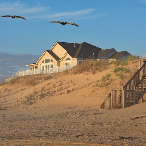 Beach house North Carolina with birds flying in front.