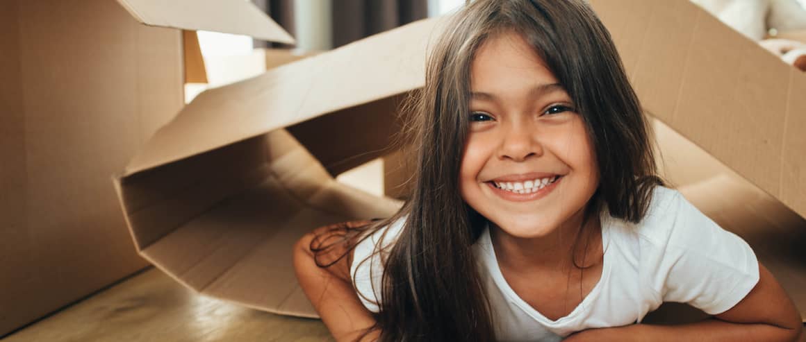 A girl playing with cardboard boxes during the unboxing of things possibly after shifting into a new home.