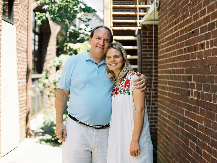 Young woman and her father hugging in front of a brick wall.