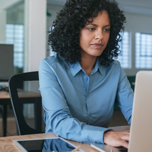 A woman in an office working on a loan application on a laptop.