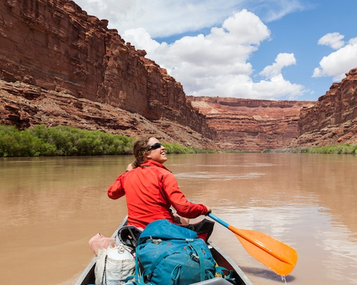 Woman paddling her canoe down a river.