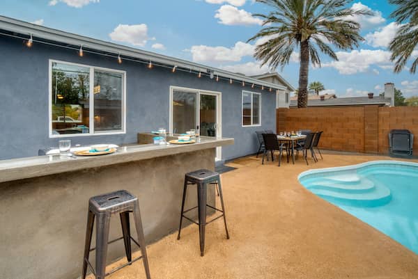 Bar counter near a pool in a private backyard with stool seating.