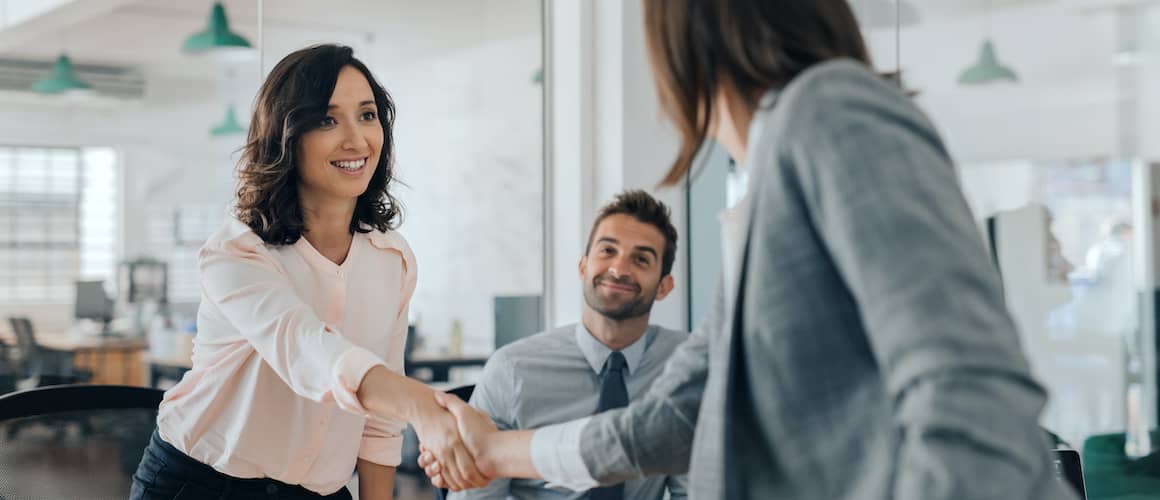 Two women shaking hands, potentially symbolizing a successful agreement or partnership.