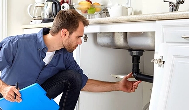 Plumber Inspecting Sink In House