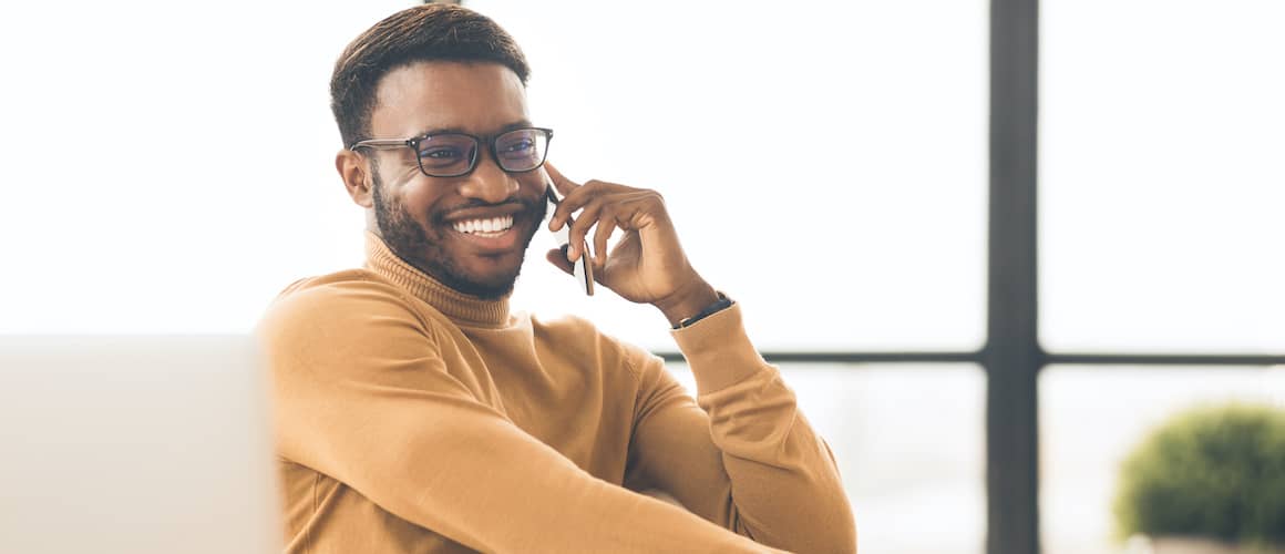 A black man on the phone, expressing happiness or contentment during a conversation.
