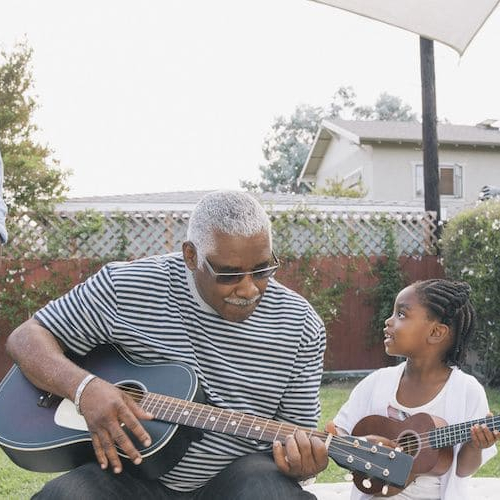Image of an African American family, enjoying in the backyard while also grilling something.