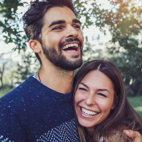 A couple smiling happily while enjoying a pleasant day in the park.