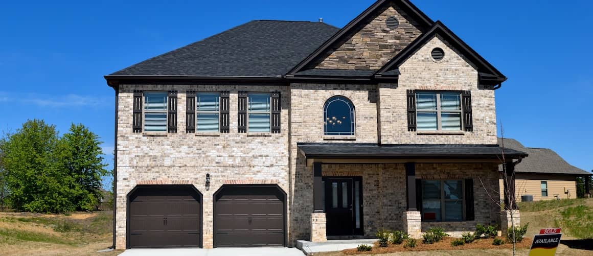 Image of a newly constructed home with white bricks and a black roof, showcasing modern residential architecture.