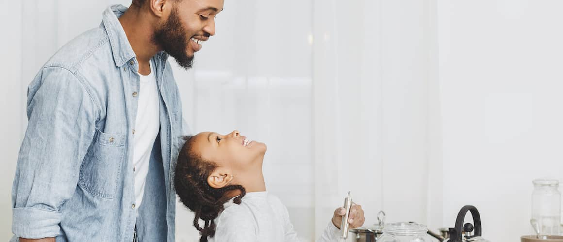 A daughter smiling and looking up at his father.